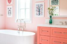 a pink bathroom with pink walls, a coral vanity, a bright printed rug and a fun gallery wall is a very whimsy space