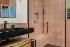 an elegant bathroom with dusty pink skinny tiles, grey terrazzo, a floating vanity, a black sink and black fixtures