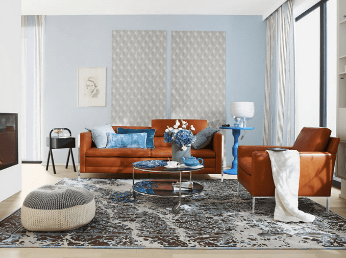The living room is done with rust colored leather furniture and blue accents