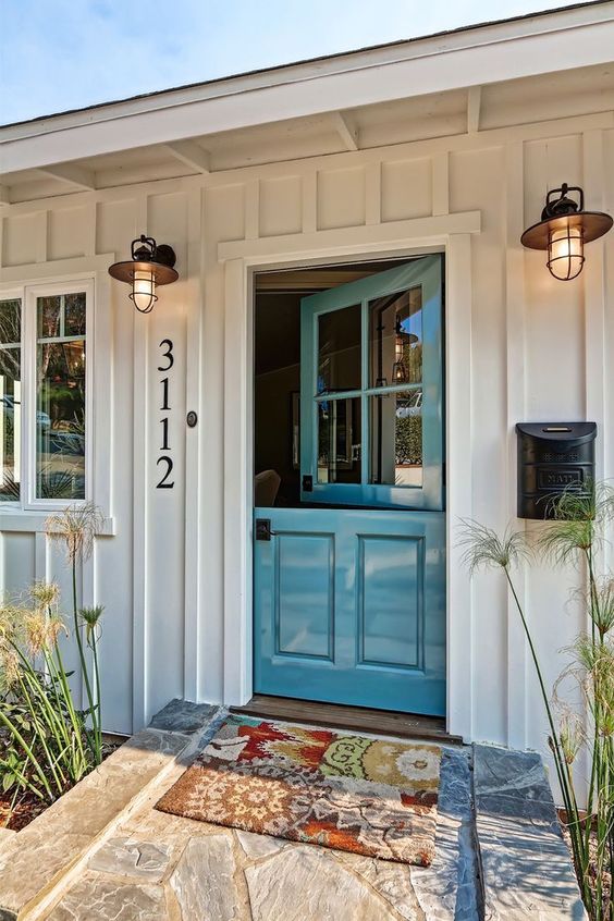A beach cottage entrance with a beautiful blue Dutch door and cute lamps