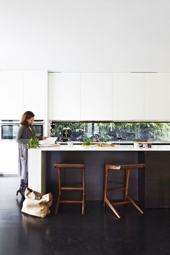 a black and white kitchen is made fresh with a window backsplash that shows off greenery