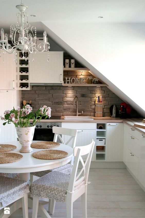 an attic kitchen with the ceiling over the sink and cooker, shelves that fit the angle