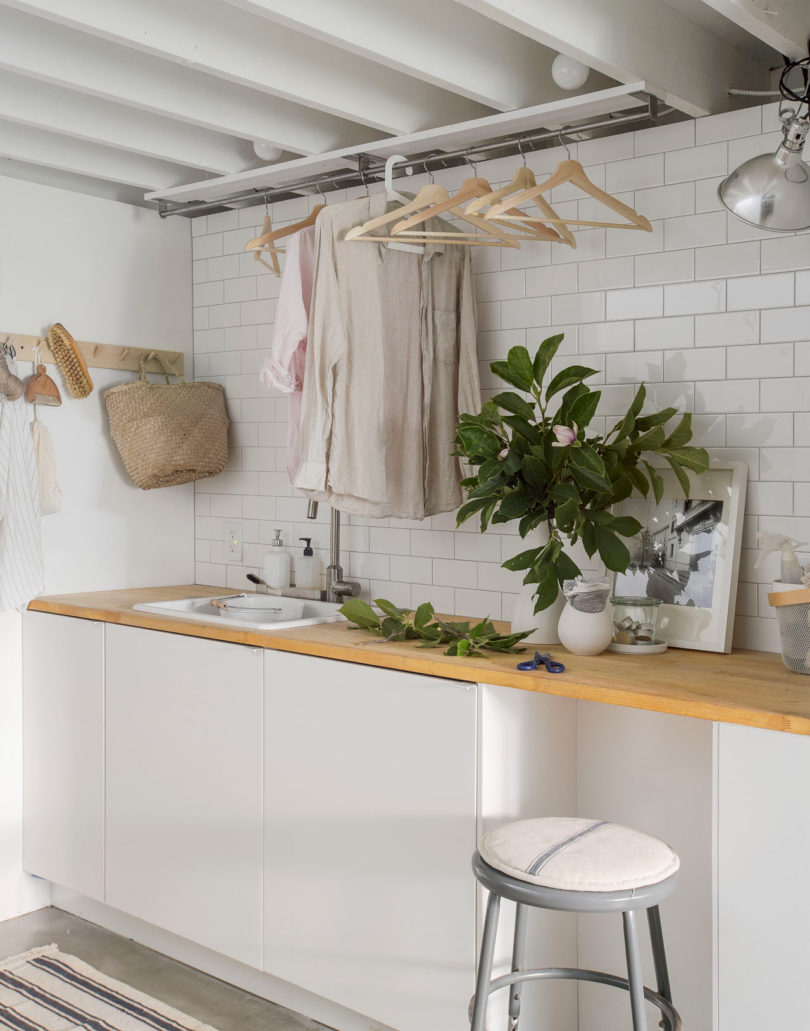 There's a laundry room with white tiles, cabinets, wooden countertops and some comfy clothes storage
