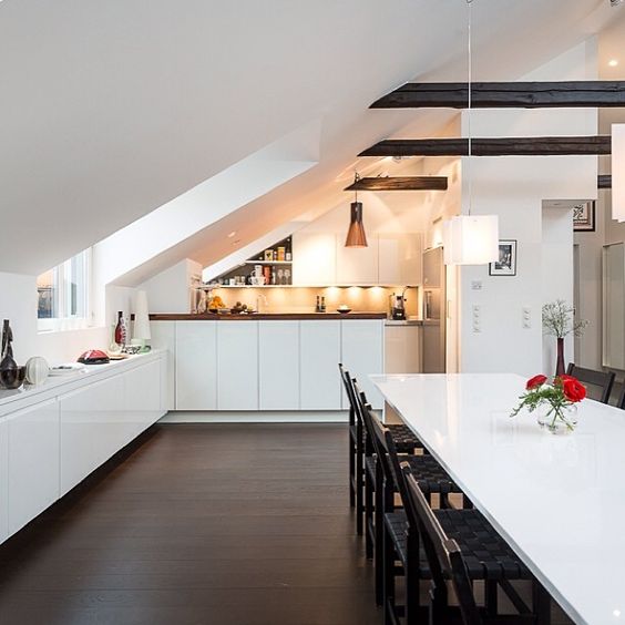 a contemporary attic kitchen in white with some dark touches and cabinets that fit the angle