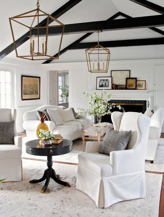 a fresh take on a farmhouse interior with two white sofas and black wooden beams for a contrast