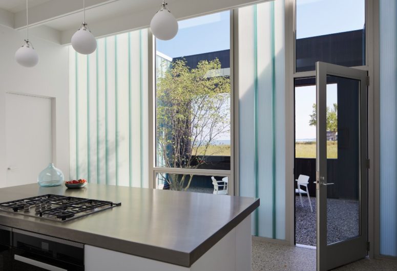 The kitchen is done with pendant lamps, cool views and sleek white cabinets, everywhere there's acess to outdoors