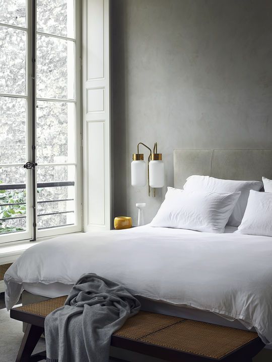 a grey plaster wall, an upholstered bench and touches of brass for pure elegance