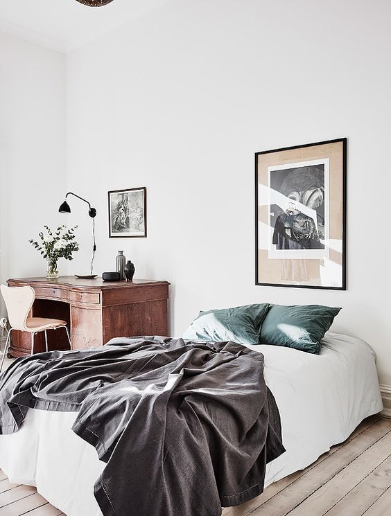 an airy and light bedroom with a bed and a vintage wooden desk in the corner