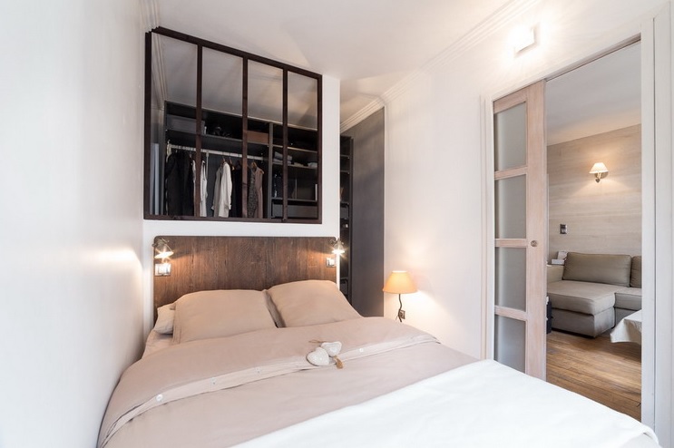 The bedroom is a tiny space with a large bed and sconces