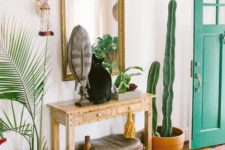 05 a boho summer console with a mask, greenery and a cactus around it and a cat on it