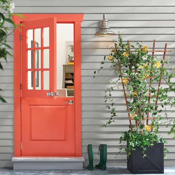 A bright space with a red Dutch door, a planter with a trellis and green rubber boots for a rustic feel