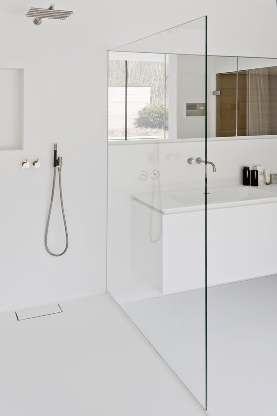 a minimalist white bathroom with a seamless shower, a long mirror and clean lines