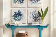 05 a turquoise console with a gallery wall of coral artworks, bottles and a basket