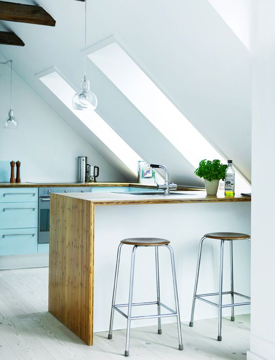 the kitchen island fits the attic angle and is surrounded with skylights