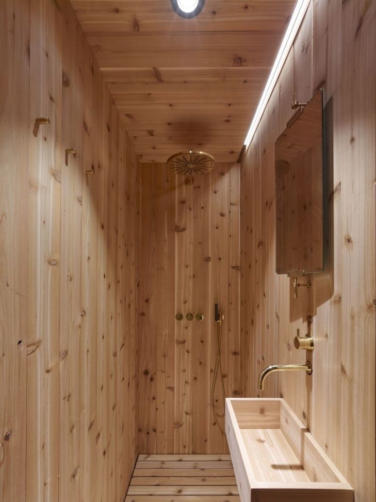 The bathroom is small, it features a shower and a sink, everything here is clad with wood