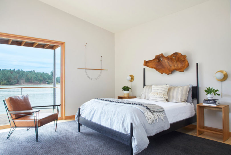 The master bedroom shows off an amazing view and a comfy bed with a rough wooden sculpture