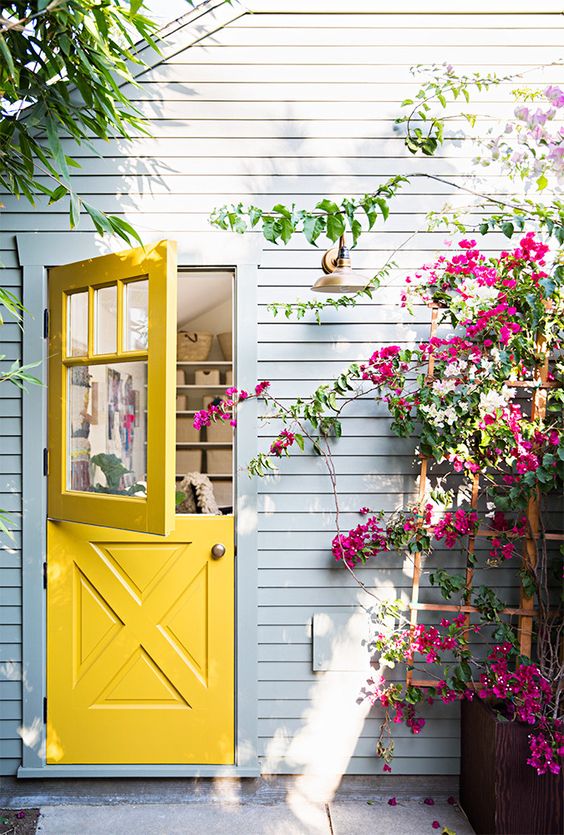 a bright yellow Dutch door, a grey wall and bold fuchsia blooms make this space wow