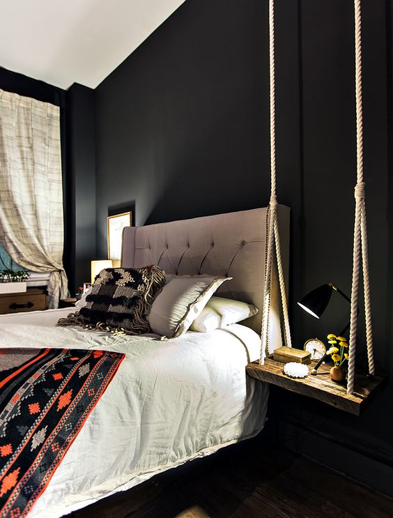 a cool modern bedroom with a boho feel and a swing-style bedside table of thick rope and a wooden piece