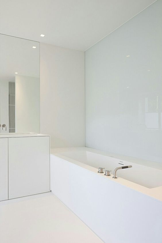 a minimalist white bathroom with a covered bathtub, a large mirror and a vanity