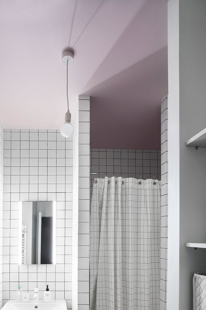 The bathroom is done with a pink ceiling and white tiles with black grout for a creative look