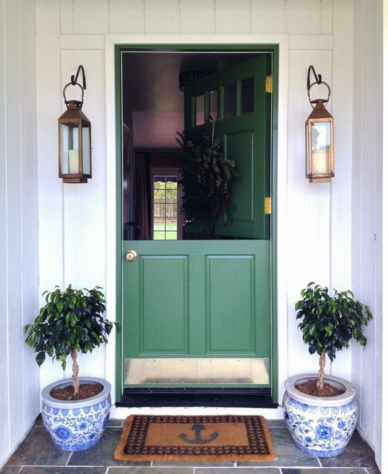 a chic green Dutch entrance door with brass touches, lanterns and pots for a cute look