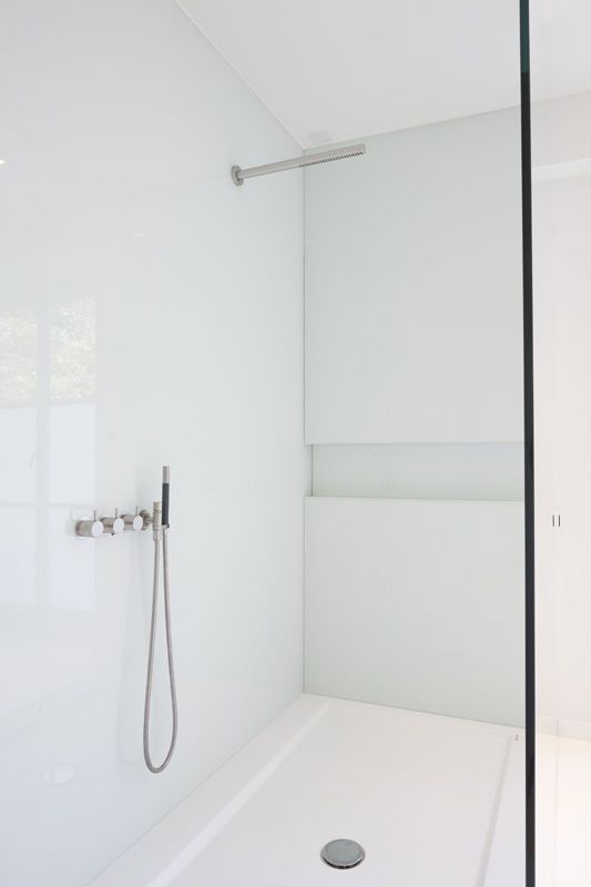 a chic white bathroom with a shower with a glass door and stainless steel touches