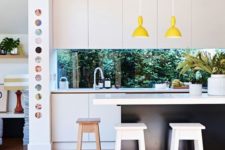 08 a contemporary black and white kitchen is spruced up with yellow lamps and a window backsplash