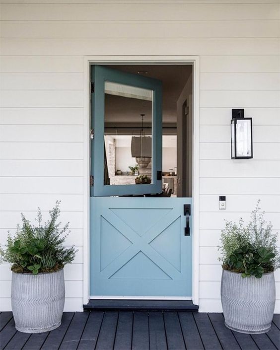 a contemporary beach entrance with a blue Dutch door and symmetrical pots with succulents