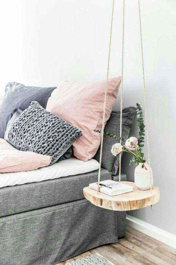 a cute hanging nightstand of rope and a wood slice for a natural touch