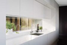 10 a minimalist kitchen in white with a window backsplash to give a touch of color and more interest to the space