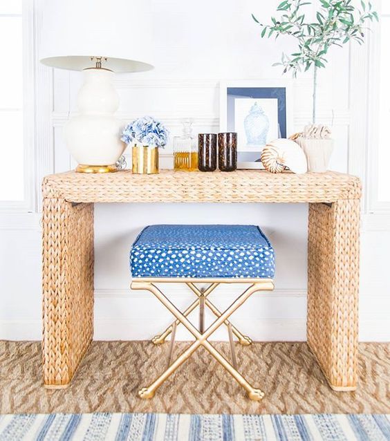 a straw console table, blue flowers, large shells, greenery and a blue chair for a beach feel
