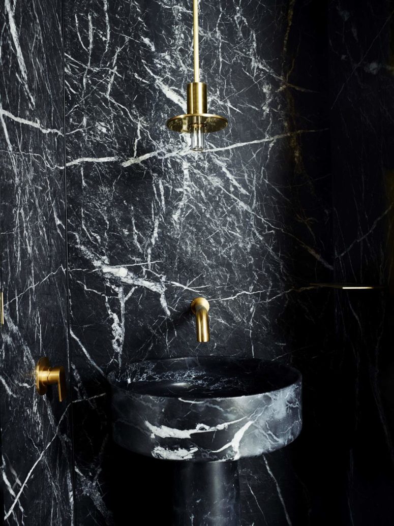 The powder room is done with brass and black marble for a chic look