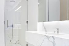 11 a minimalist white marble bathroom with a large mirror, a shower and a marble vanity