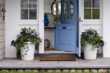 a cute blue Dutch door and matching potted flowers on both sides to make the entrance welcoming