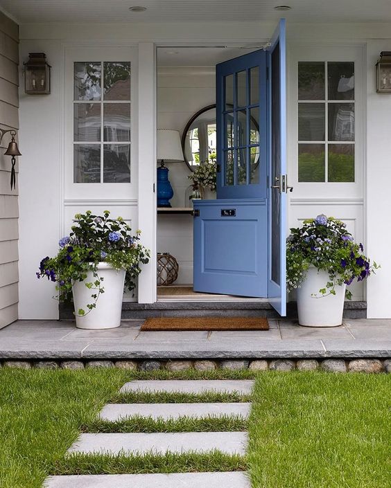 a cute blue Dutch door and matching potted flowers on both sides to make the entrance welcoming