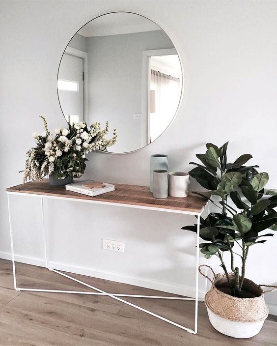 a minimalist summer console table with lush blooms in a vase and a potted plant in a basket - you won't need more