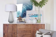 12 a modern console with a couple of oceanside artworks and tropical leaves in a vase