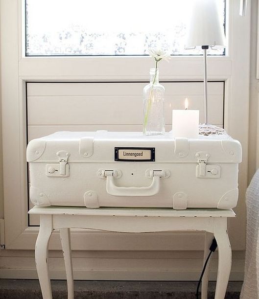 a vintage suitcase painted white and put ona  white table for a shabby chic bedroom