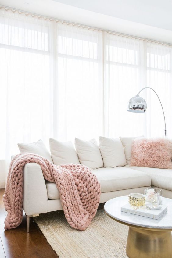 An all white living room is injected with blush pink accessories and touches of metallics