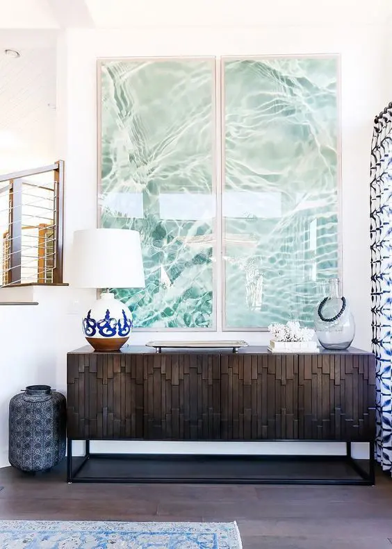 a modern beach console done with a water-inspired artwork duo, corals and a large bottle
