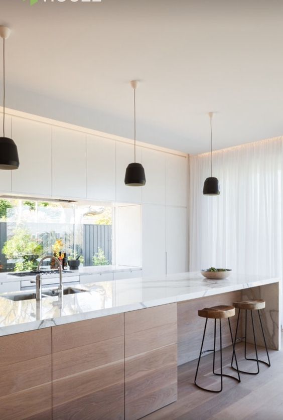 a white minimalist kitchen with wooden touches and a window backsplash for much light in the space