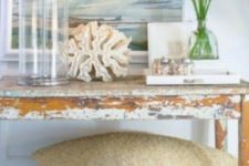 15 a distressed console table, a glass lamp, a large coral and a seascape artwork for a dreamy feel