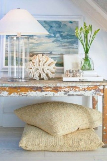 a distressed console table, a glass lamp, a large coral and a seascape artwork for a dreamy feel