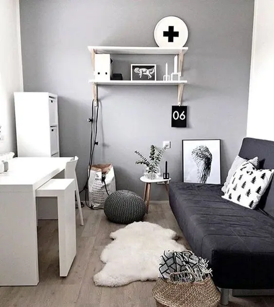 a Scandinavian bedroom with a black transformable sofa and a white desk plus some drawers