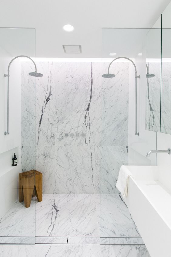 white marble tiles and a wooden stool bring texture and eye-catchiness to the space