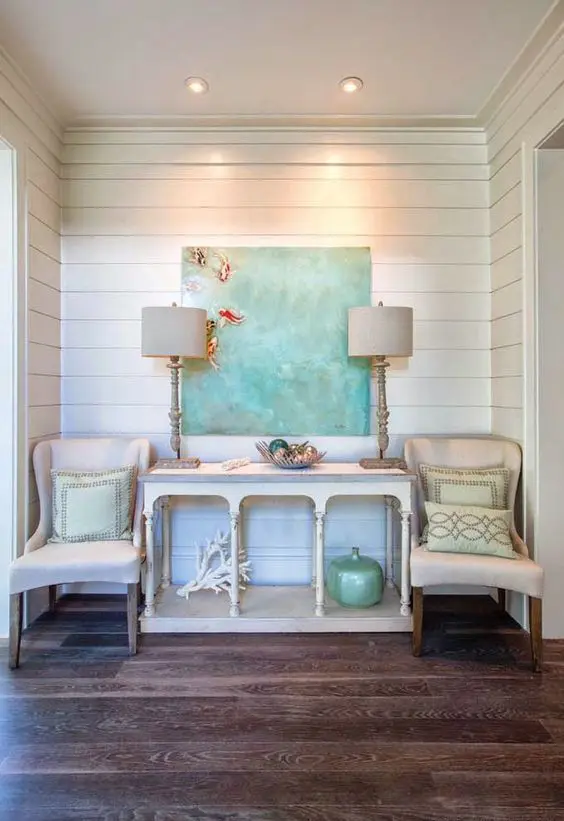 a beach console table, a coral, a bottle, a driftwood bowl and an oversized artwork