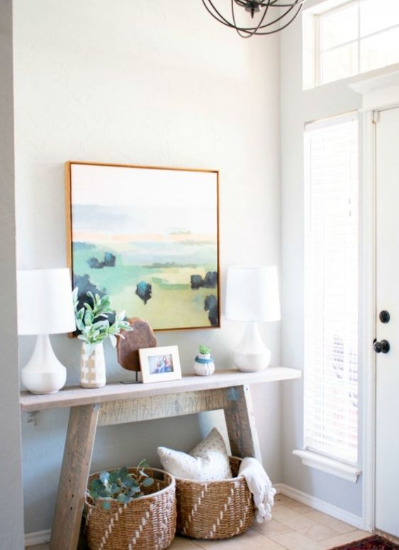 a summer console with an abstract artwork, baskets and greenery for a cozy feel