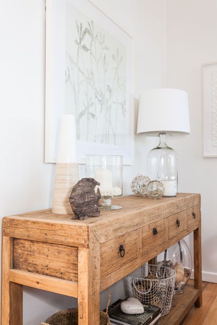 a beach console, a glass base lamp, a fish of driftwood and some floats