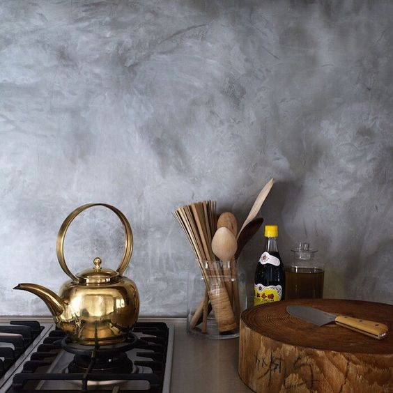 a grey plaster backsplash, brass and wood create a fantastic ambience in the kitchen