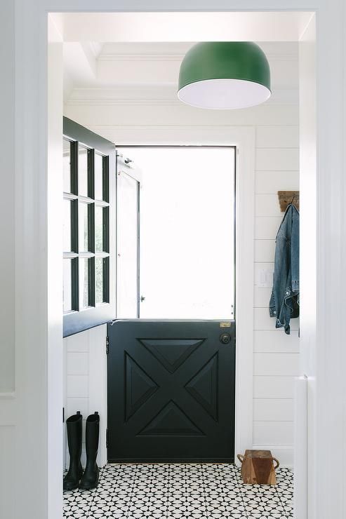 a modern farmhouse entryway with a black Dutch door and a mosaic black and white floor